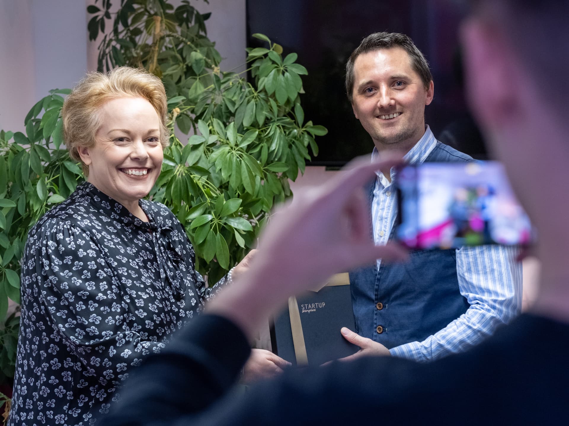 Two people from the Startup Disruptors community with a branded folder